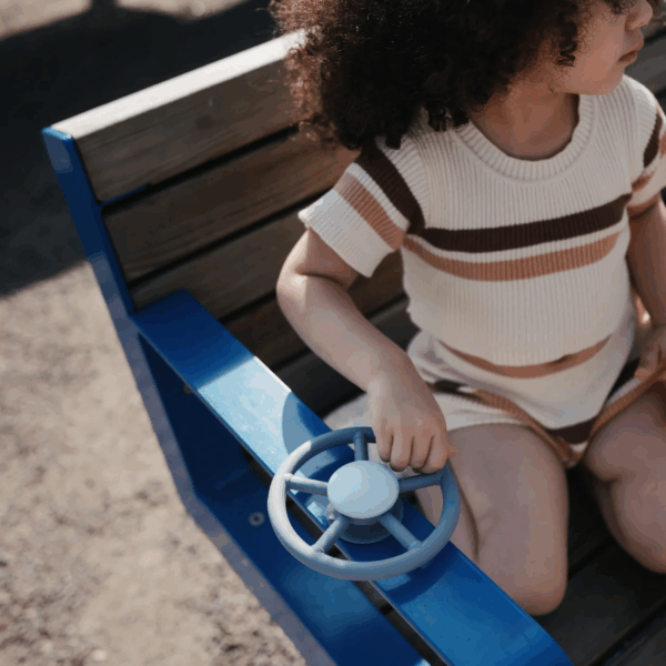 Vue de côté du Mushie wheel Suction Spinner Toy posée sur une surface lisse