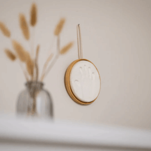 Cadre rond en bois suspendu contenant l’empreinte bébé