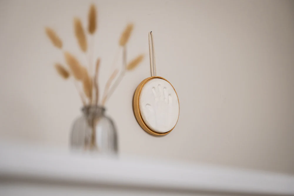 Cadre rond en bois suspendu contenant l’empreinte bébé