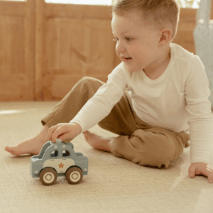 Enfant jouant à la voiture de police en bois Bleu Little Dutch sur sol de jeu